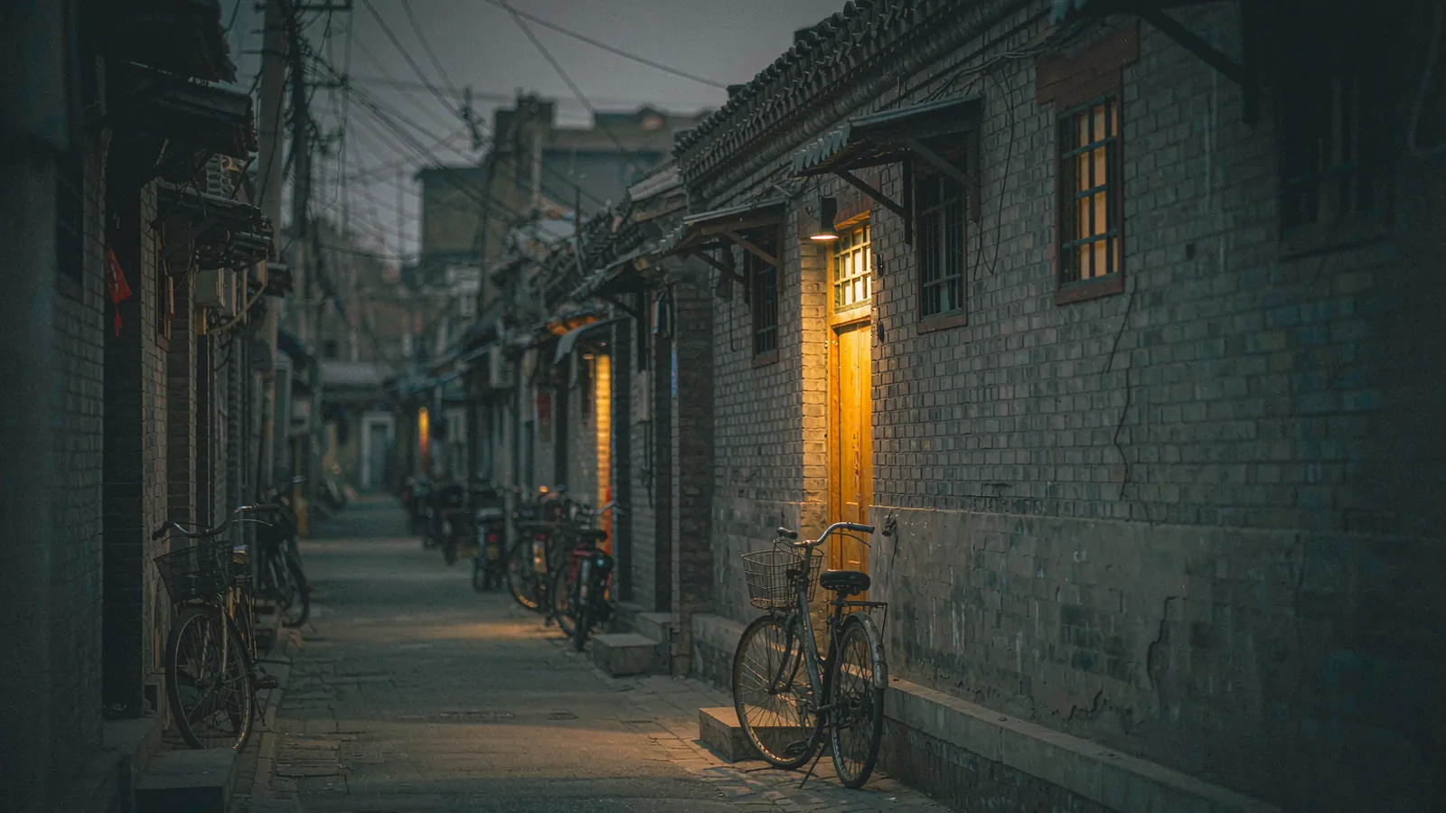 Pátio de um hutong em Pequim com bicicletas e plantas, ao final da manhã