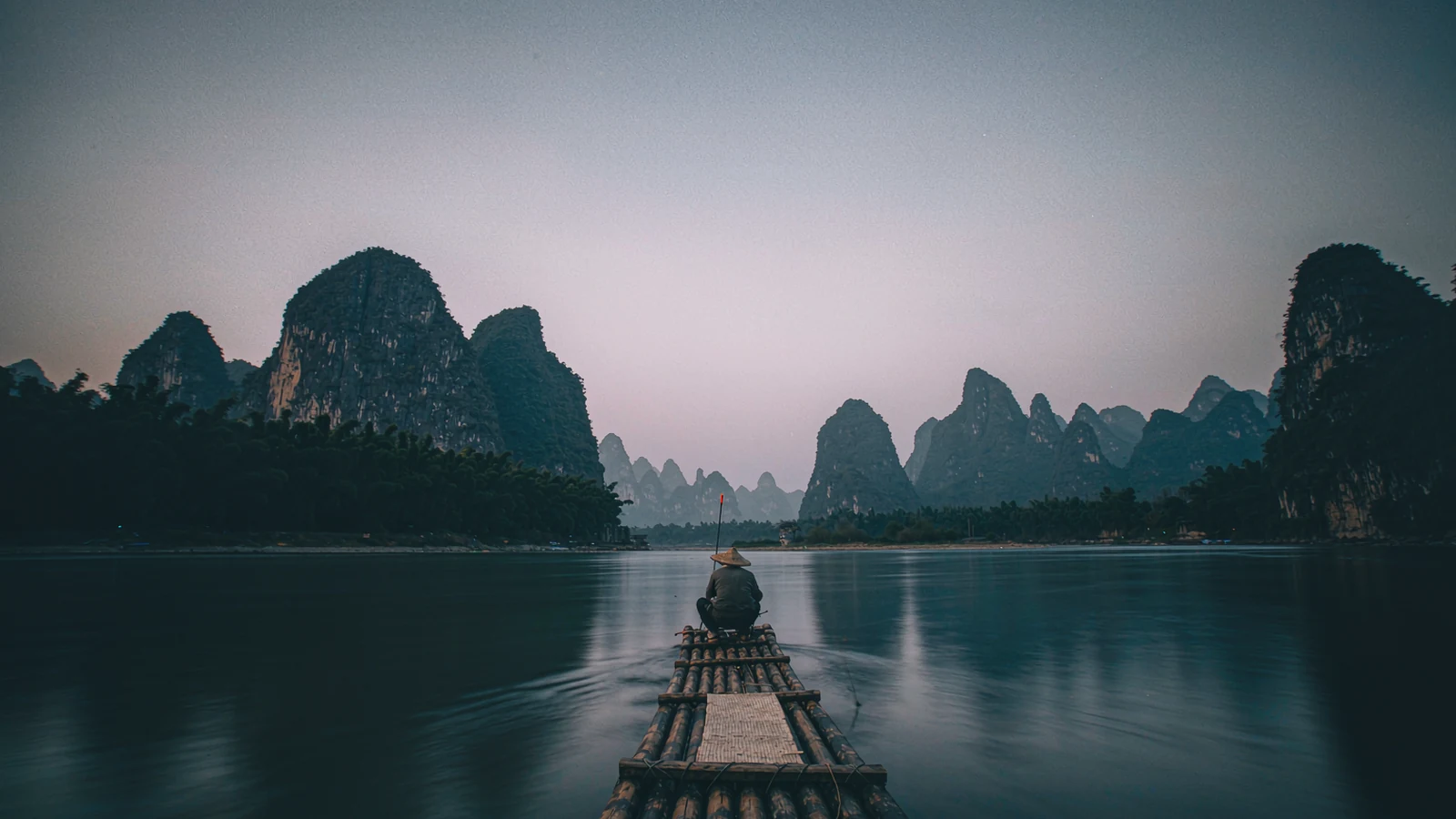 Jangada de bambu descendo o rio Li, com os picos cársticos de Yangshuo ao fundo