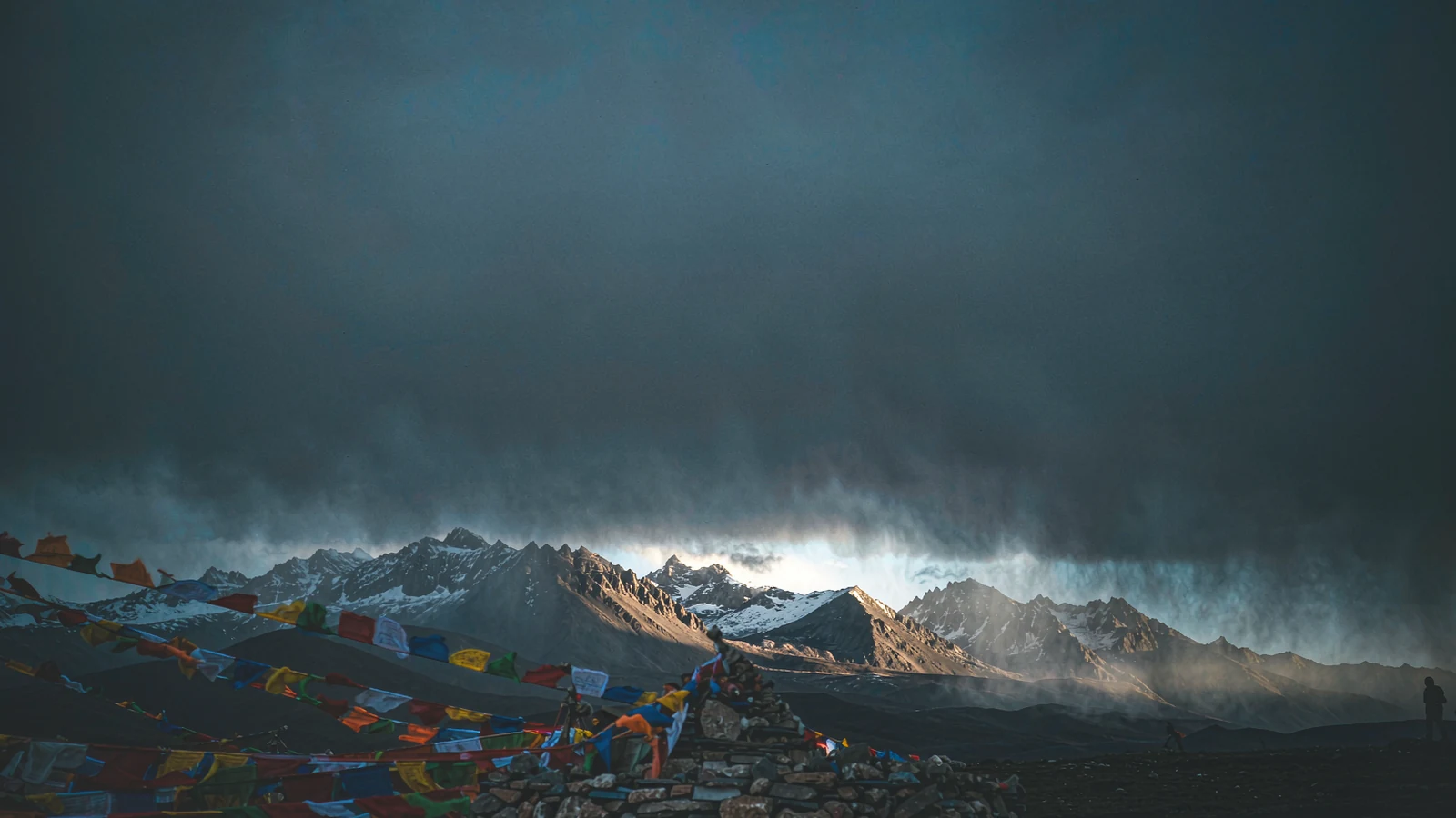 Tibetan prayer flags and a mani stone mound with carved plaques on the plateau