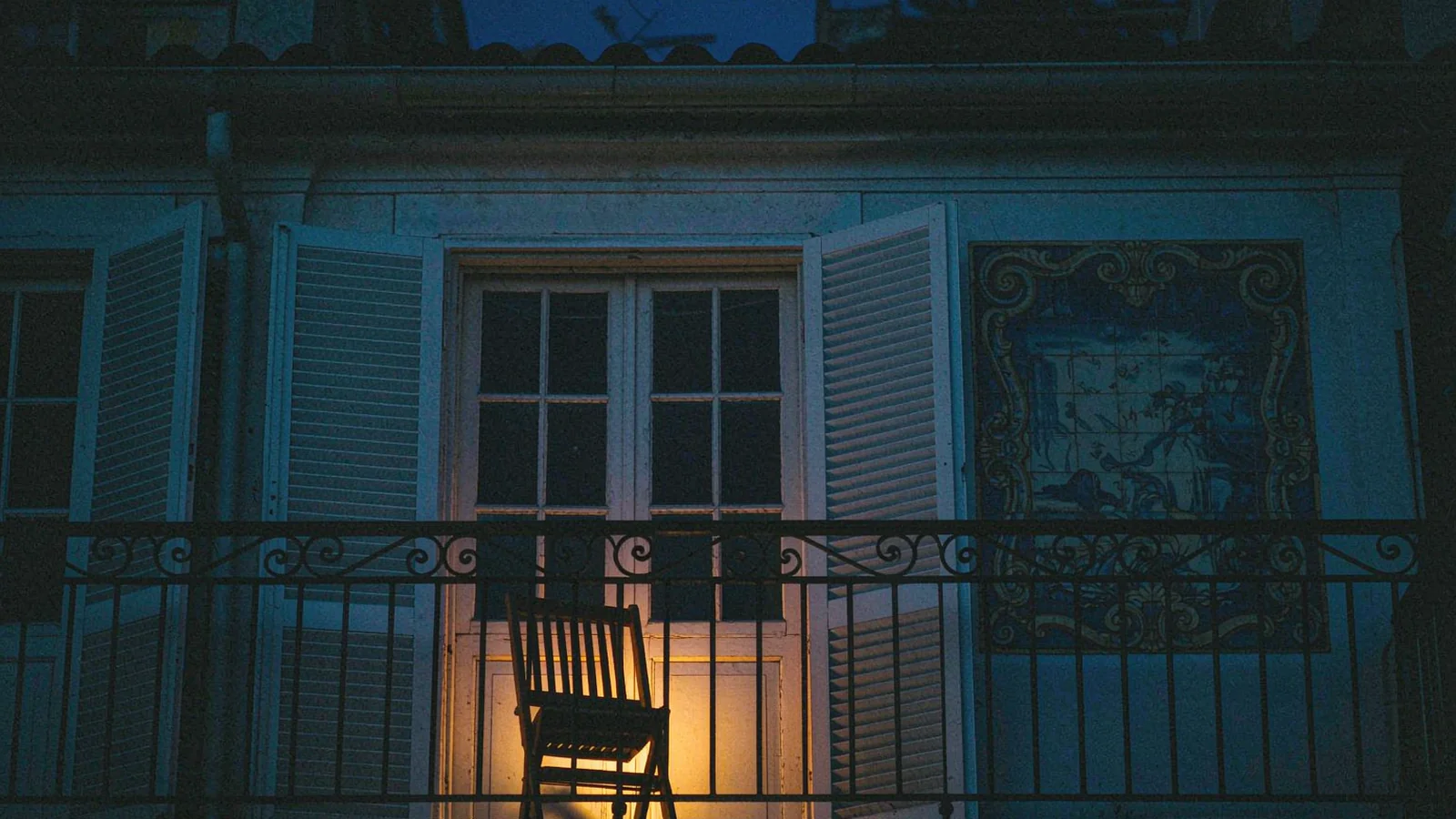 Iron balcony and green shutters on a low house in the historic centre of Macau, late afternoon